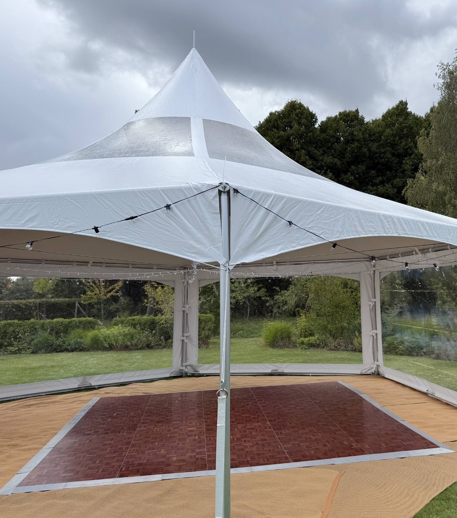 Parquet dancefloor centred under a pagoda-style marquee with festoon lighting